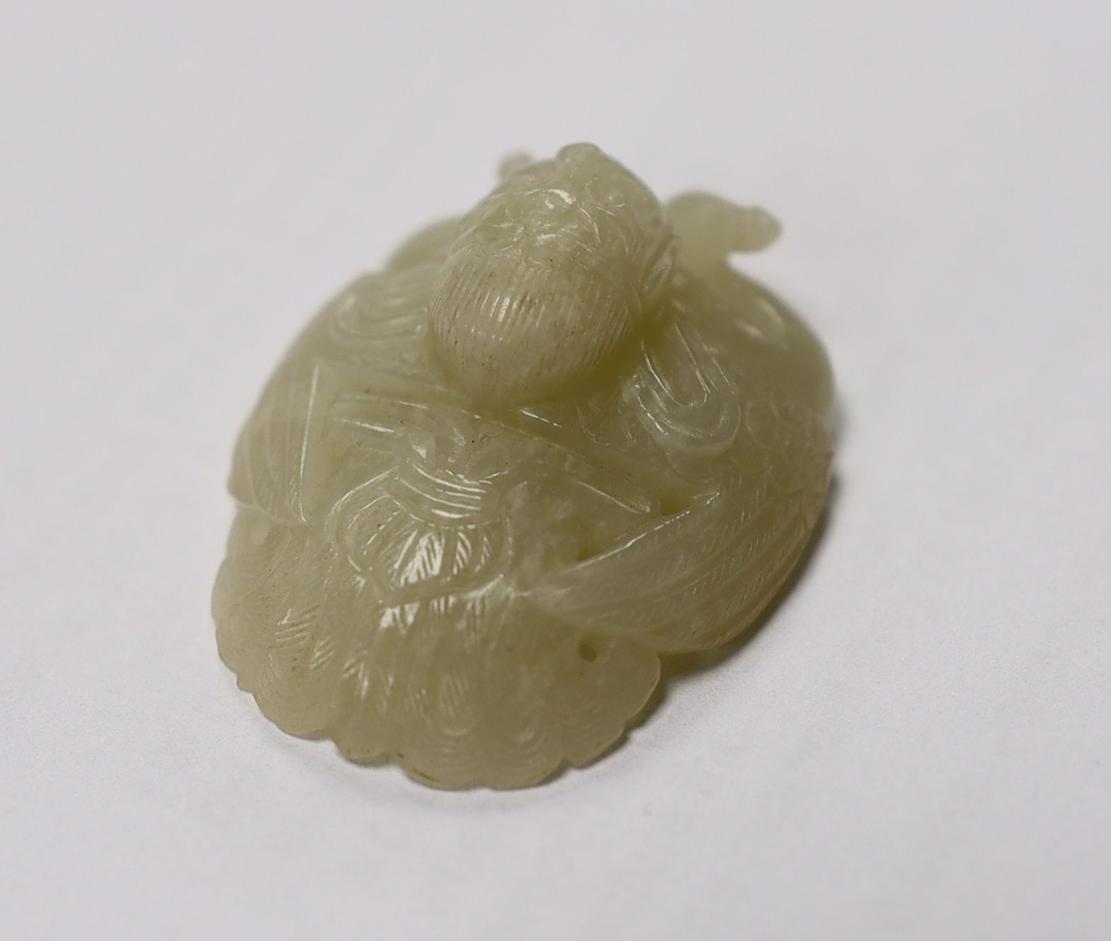 A Chinese pale celadon jade mount carved as a mythical half-man half-bird creature, 18th/19th century, 3.8cm high